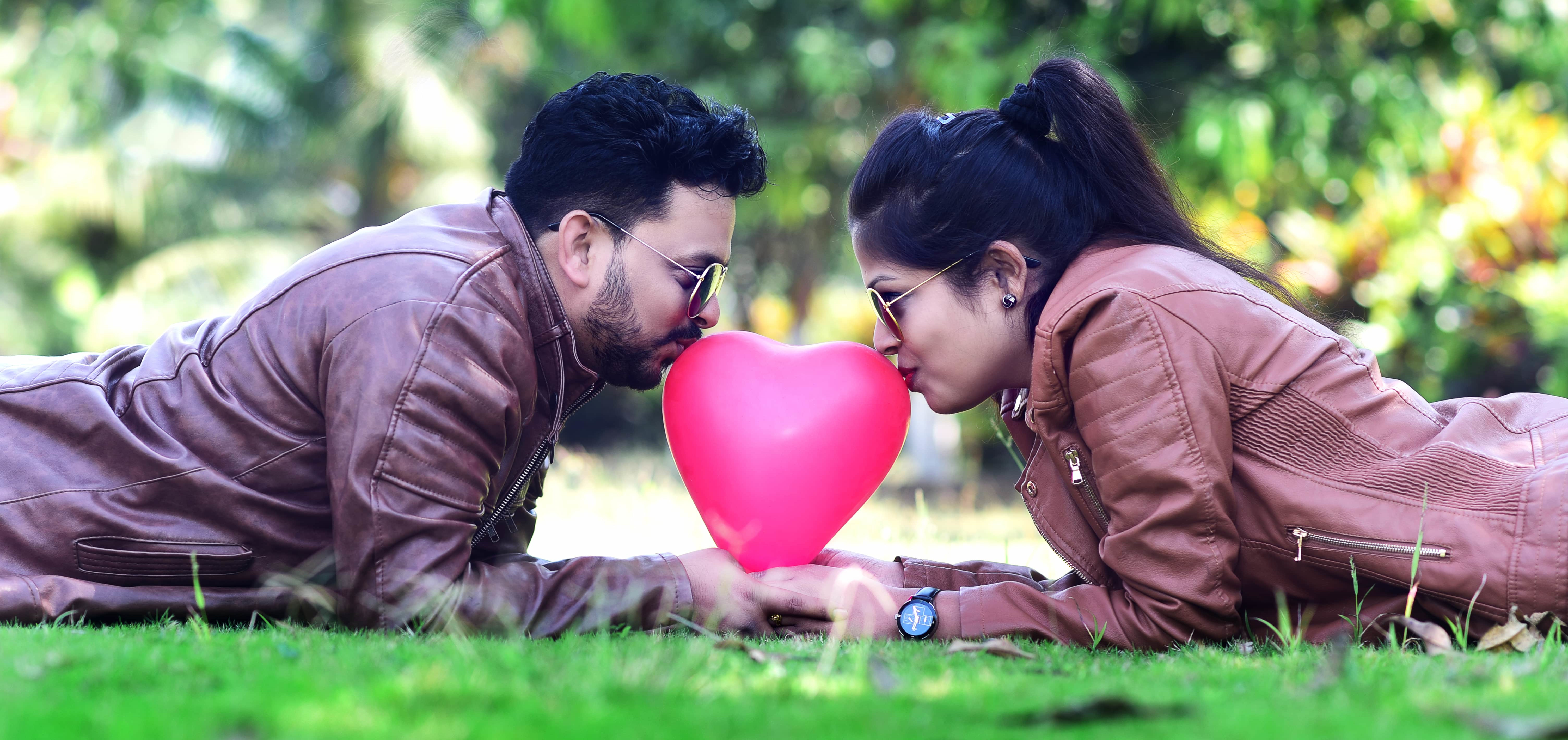 Couple with a heart balloon lying on grass